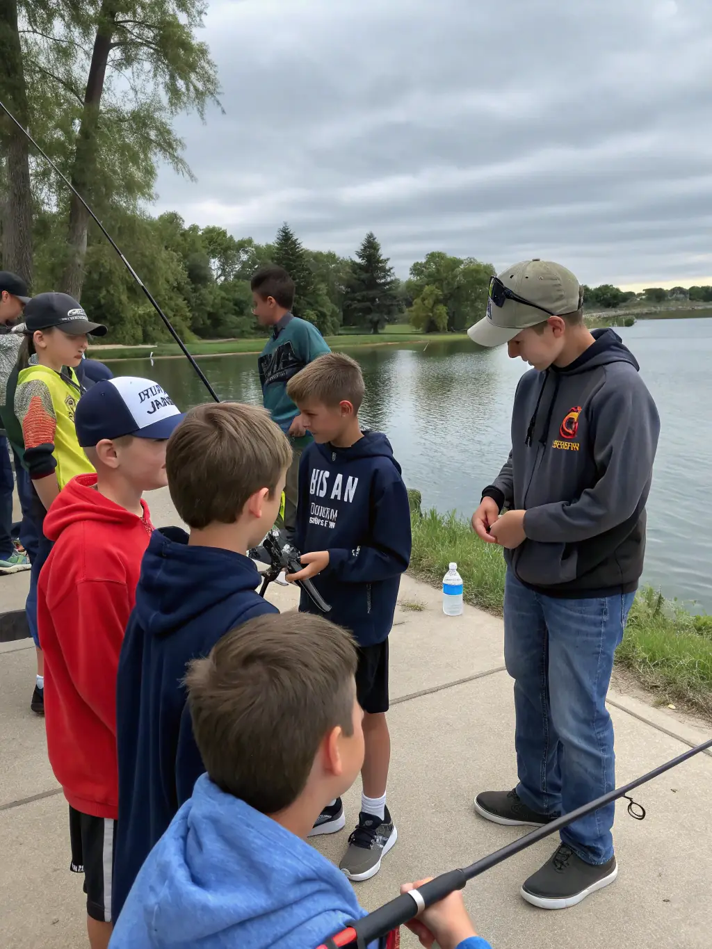 A photograph showcasing a group of children learning about responsible fishing techniques during an educational workshop conducted by AAPPMA LA GARLECHE, with instructors demonstrating proper handling of fishing gear.